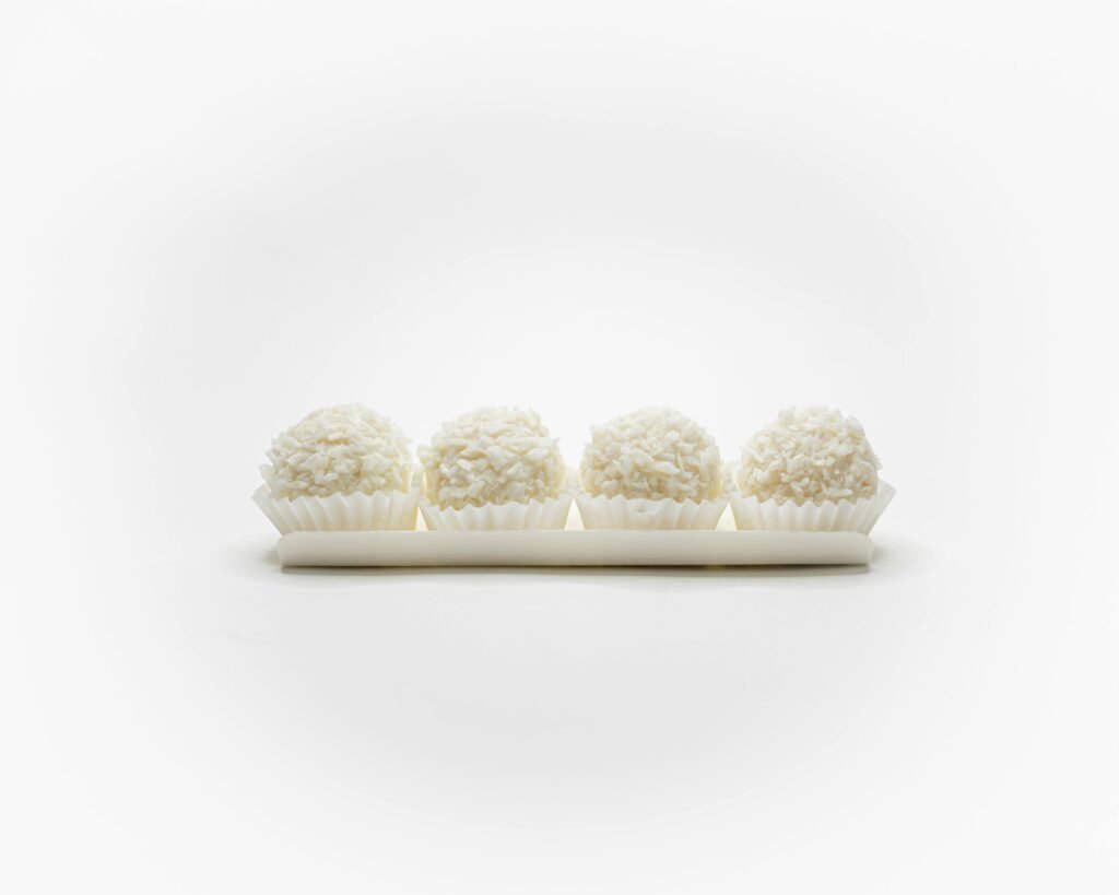 Set of four white coconut pralines, elegantly arranged in a minimalist style on a white background.