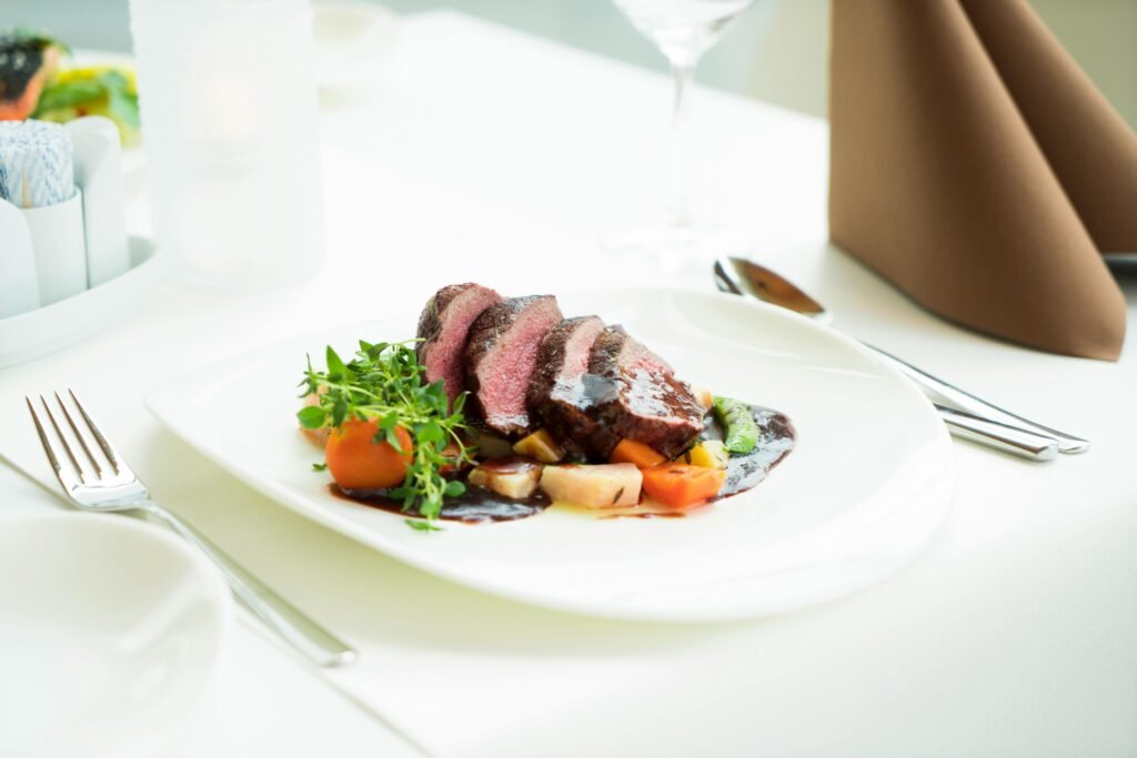 A beautifully presented beef steak with vegetables and sauce in a fine dining setting.