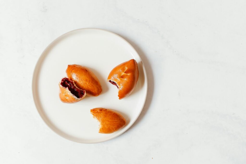 A top view of traditional Russian pirozhki pastries on a white plate, showcasing their delicious filling.